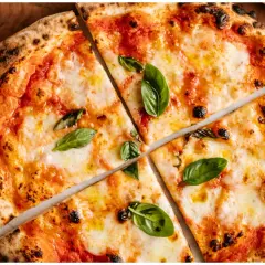Margherita z puszystym ciastem i prawdziwym sosem do pizzy, ozdobiona świeżą bazylią.