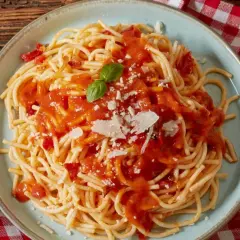 Spaghetti z sosem pomidorowym, parmezanem i bazylią na talerzu.