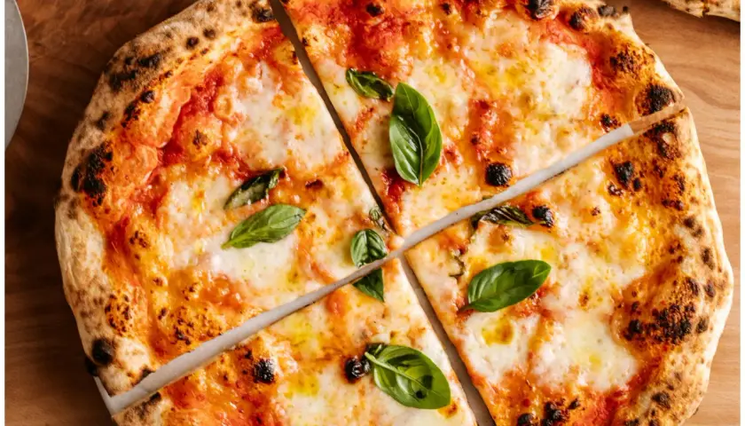 Margherita z puszystym ciastem i prawdziwym sosem do pizzy, ozdobiona świeżą bazylią.