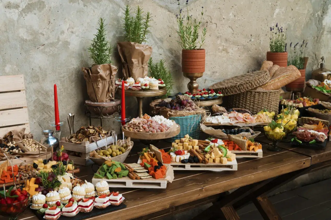 Bogaty stół z przekąskami: sery, owoce, ciastka, pieczywo. Zastanawiasz się, ile kosztuje catering na 20 osób? Taka uczta to marzenie!